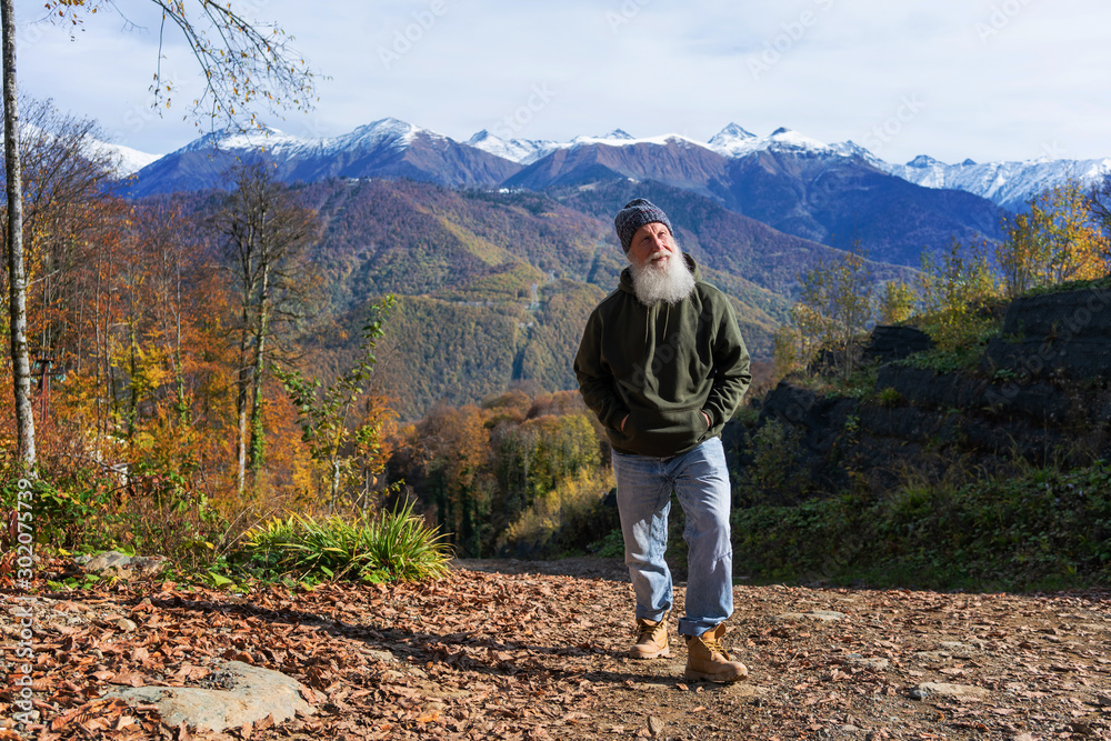 gray-haired ld man with a beard conquers the summit, concept of tourism and recreation in old age gray-haired ld man with a beard conquers the summit, concept of tourism and recreation in old age