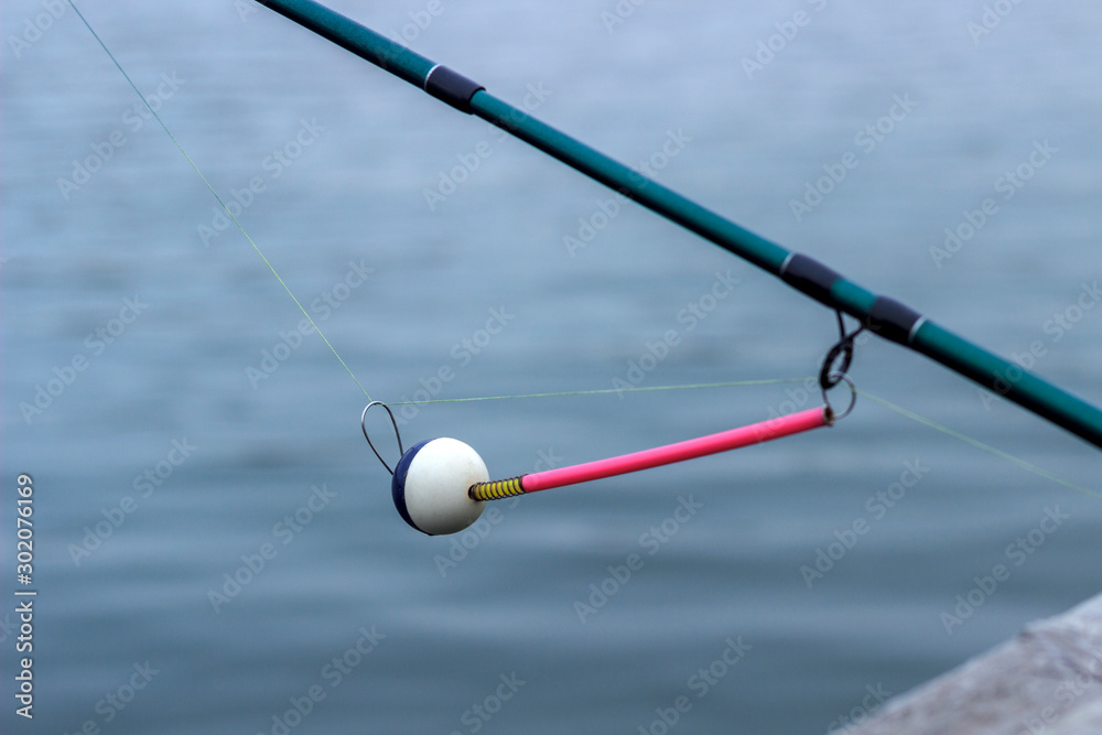 spinning bite indicator, a nod on a fishing rod by the river spinning bite indicator, a nod on a fishing rod by the river