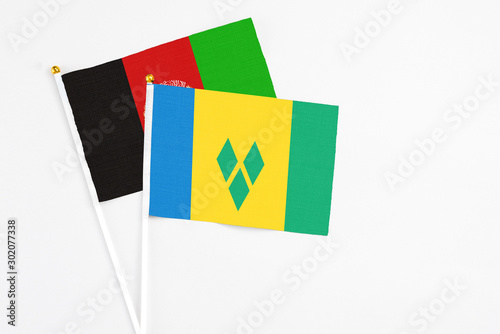 Saint Vincent And The Grenadines and Afghanistan stick flags on white background. High quality fabric, miniature national flag. Peaceful global concept.White floor for copy space.