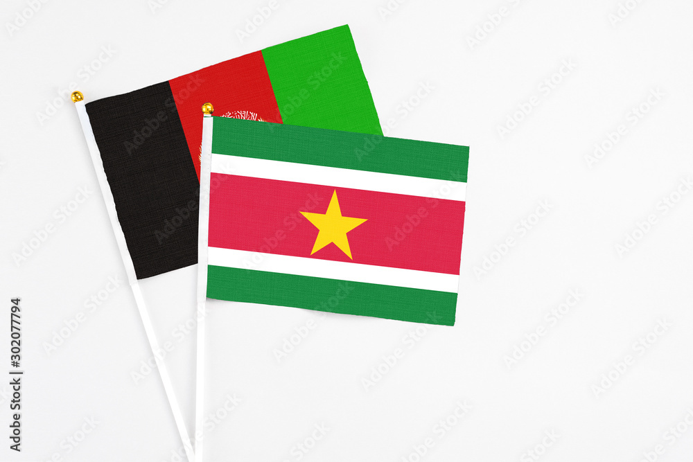 Suriname and Afghanistan stick flags on white background. High quality fabric, miniature national flag. Peaceful global concept.White floor for copy space. Suriname and Afghanistan stick flags on white background. High quality fabric, miniature national flag. Peaceful global concept.White floor for copy space.