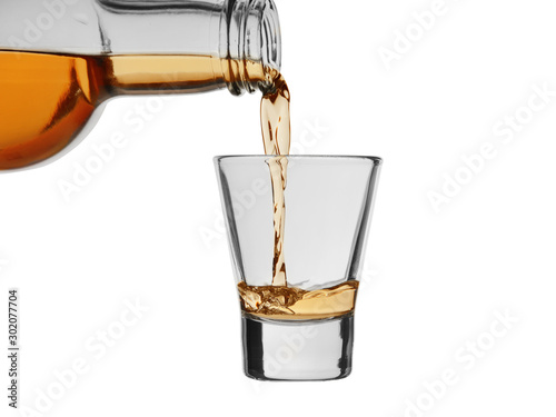 Strong alcoholic drink pour from a bottle into a wineglass isolated on a white background