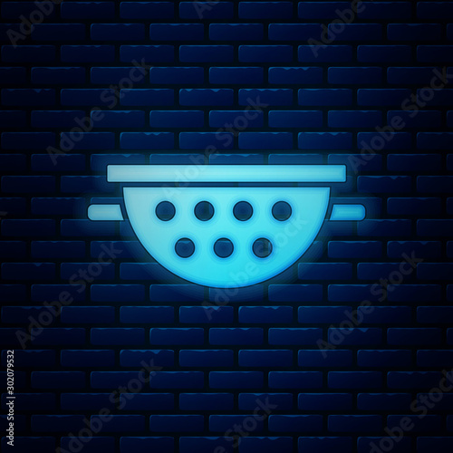 Glowing neon Kitchen colander icon isolated on brick wall background. Cooking utensil. Cutlery sign. Vector Illustration