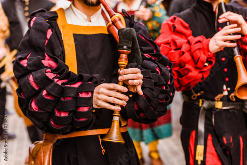 фотографія Medieval troubadour playing an old flute with other musicians in disguise