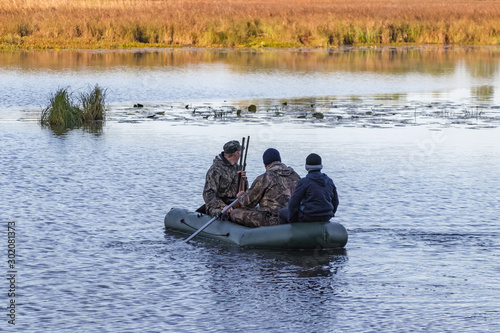 Hunters in a boat swim in a pond in search of wild ducks