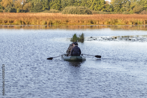 Hunters in a boat swim in a pond in search of wild ducks