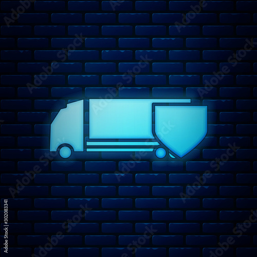 Glowing neon Delivery cargo truck with shield icon isolated on brick wall background. Insurance concept. Security, safety, protection, protect concept. Vector Illustration