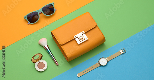 Fashion Lady layout Flat lay. Minimal. Woman Essentials accessories, cosmetic makeup. Trendy Clutch, sunglasses. Coloful orange green party girl Set. Creative pop art fashionable vibrant concept