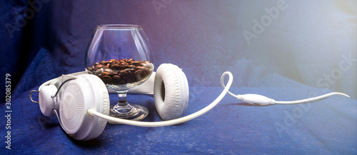 Tableau sur toile Glass with coffee beans and white headphones