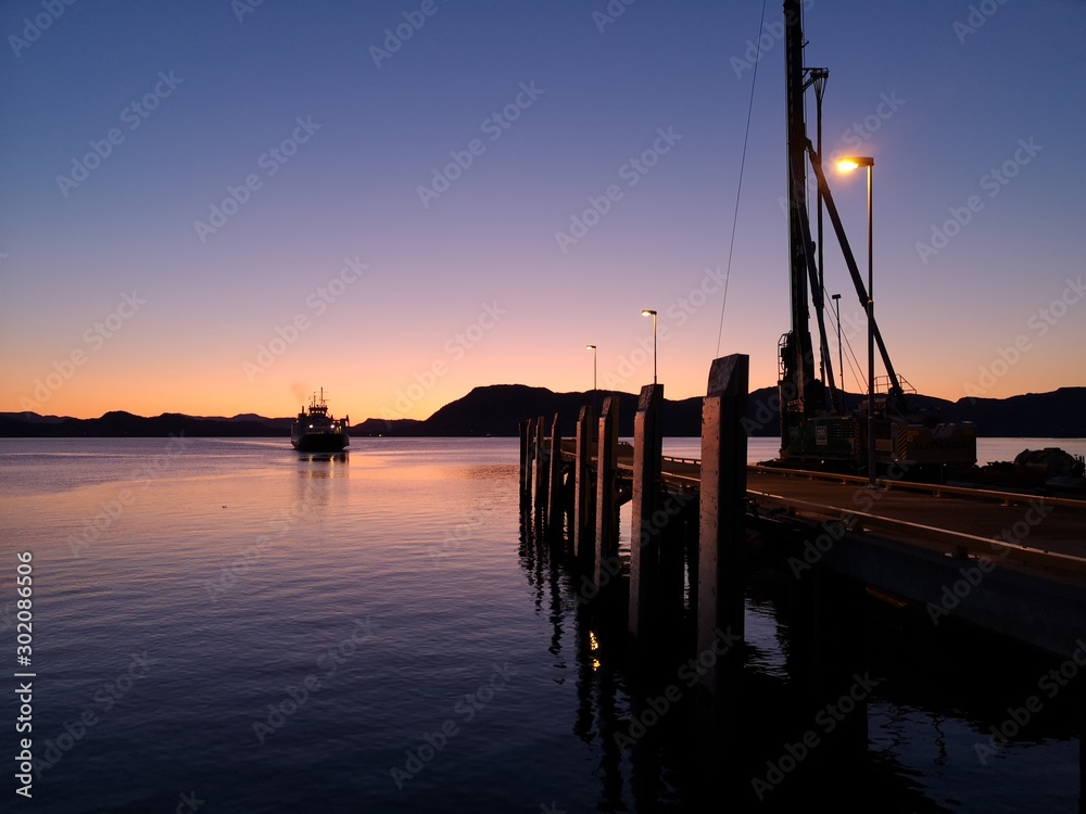 Ferry docking in a norwegian fjord port at evening