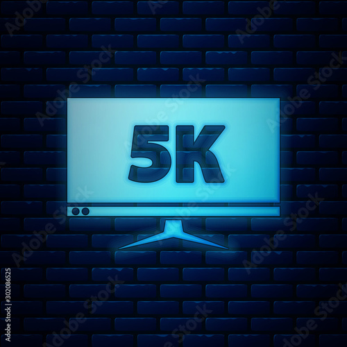 Glowing neon Computer PC monitor display with 5k video technology icon isolated on brick wall background. Vector Illustration