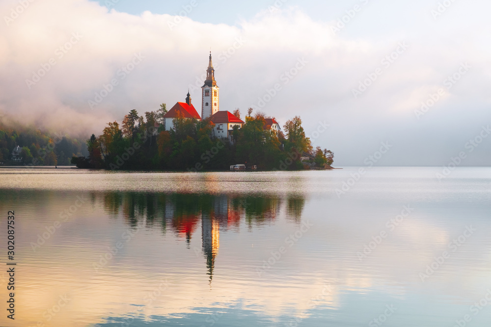 Naklejka premium Famous Bled Lake in Triglav National Park in the Julian Alps with a forest in autumn colors at sunrise