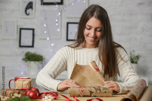 Fotografie Happy smiling woman wrapping Christmas presents, winter holidays, gifting season