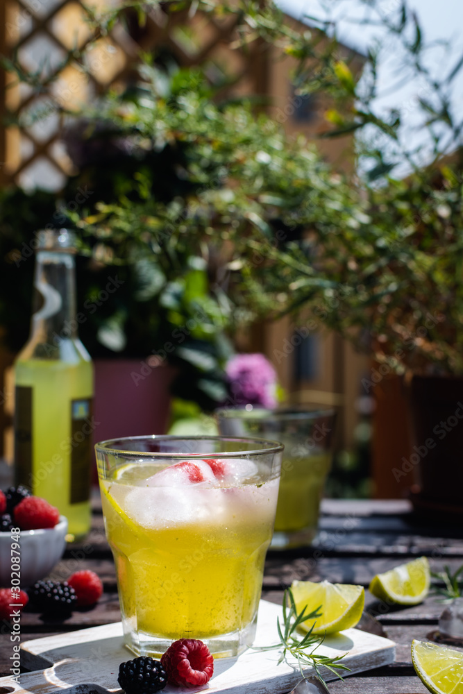 Cold refreshing tarragon, blackberry and raspberry lemonade with ice on wooden rustic table i
