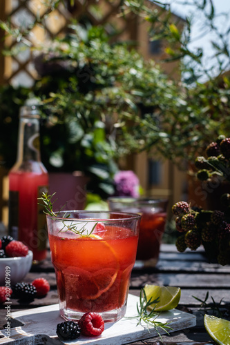 Cold refreshing lime, blackberry and raspberry lemonade with ice on wooden rustic table