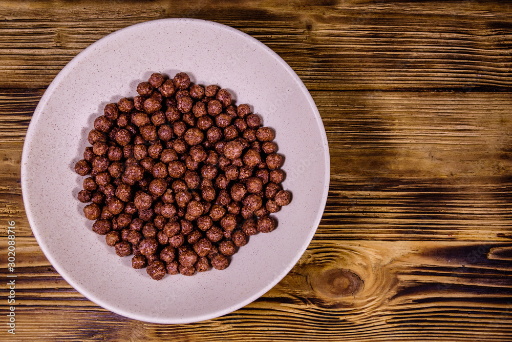 Ceramic plate with chocolate cereal balls on wooden table. Top view Ceramic plate with chocolate cereal balls on wooden table. Top view