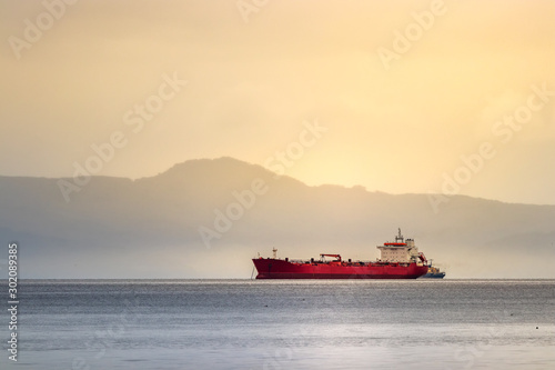 A red tanker ship sailing at high seas in the Bering sea at sunset.