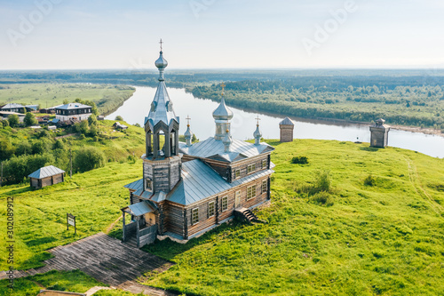 Old russian orthodox church made of wood on hill top near river in Cherdyn village, aerial view. Rural landscape with historic christian religious building in Perm krai, Ural, Russia photo