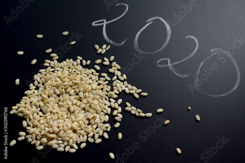 Raw brown rice over black background with number 2020 from above