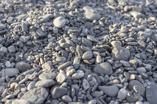 Small stone. Wet black sand. Pebble beach. Sand texture. Sandy background. Warm stones. Rounded small stones. Stone mound. Natural materials.
