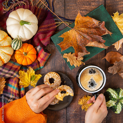 Autumn background. Decorative pumpkins, foliage hands and coffee with cookies on wooden background.top view.