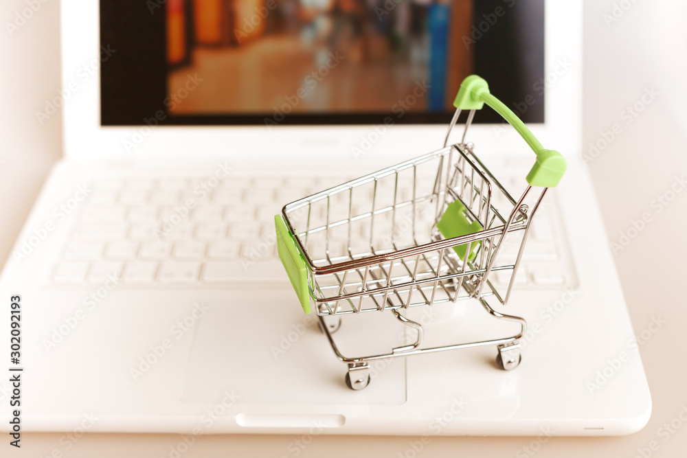 supermarket shopping cart on laptop background close-up, macro, online shopping concept and purchasing power, consumer shopping cart