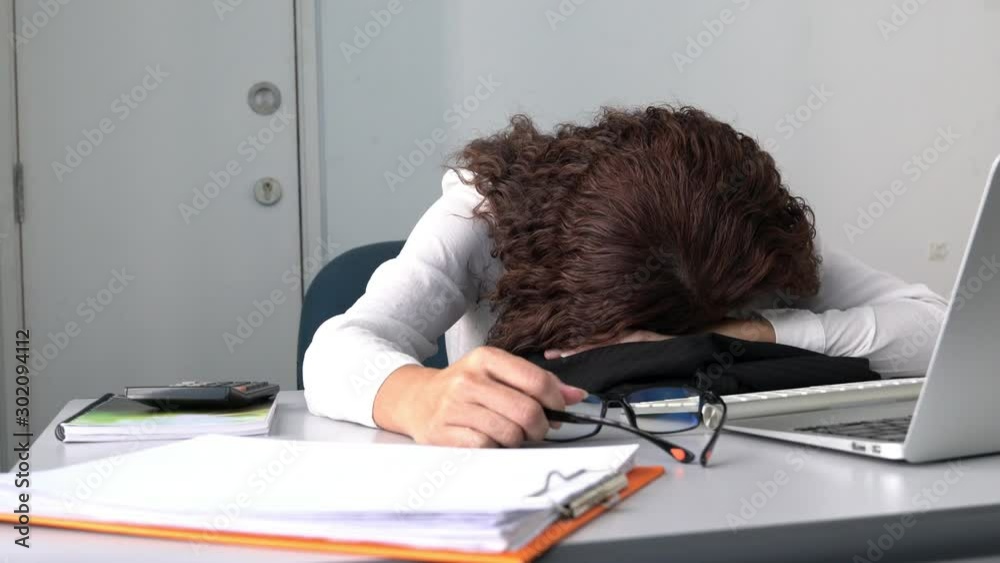 Tired employee or office executive sleeping on her office desk in front of her computer. Overwork or tired from work concept.