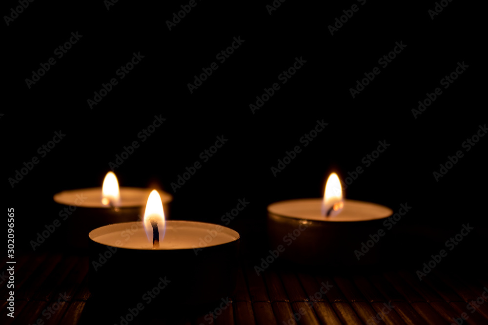 Three burning candles, close up and selective focus on foreground