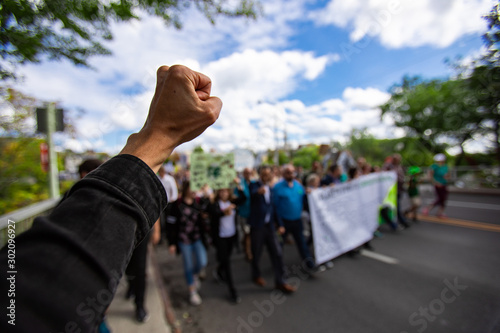 First person perspective and Selective focus on man fist raised during an ecological protest. Crowd of people walking peacefully for the environnement photo
