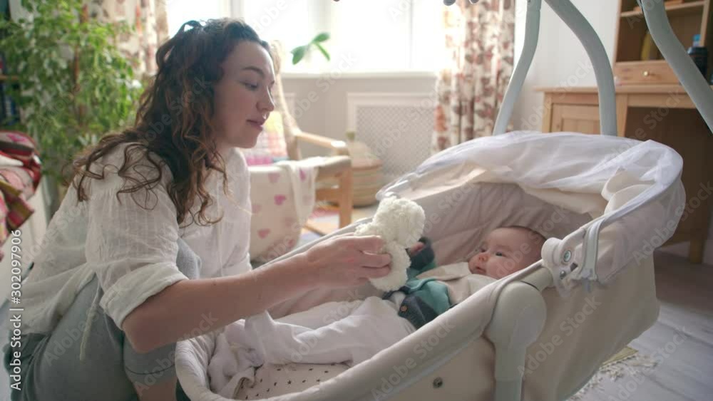 Young mother playing with newborn baby in cradle. Young mother playing with newborn baby in cradle.