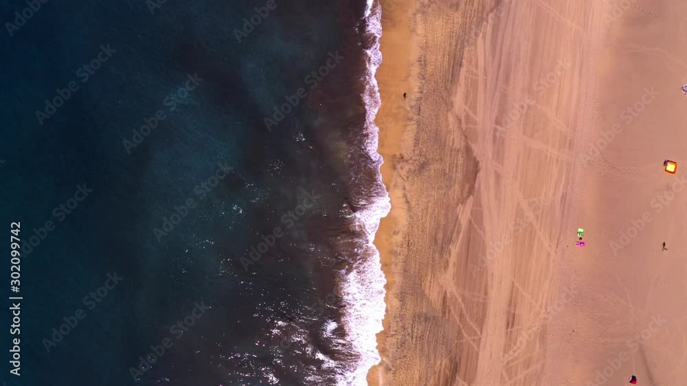 Drone tilt up over beach in Las Palmas off-season, reveal empty and red umbrellas. Drone tilt up over beach in Las Palmas off-season, reveal empty and red umbrellas.