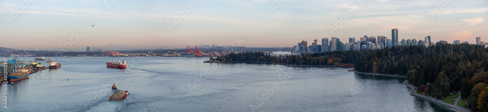 Downtown Vancouver, British Columbia, Canada. Beautiful Aerial Panoramic View of Seawall in Stanley Park with Downtown City in Background during a sunny Autumn Sunset.