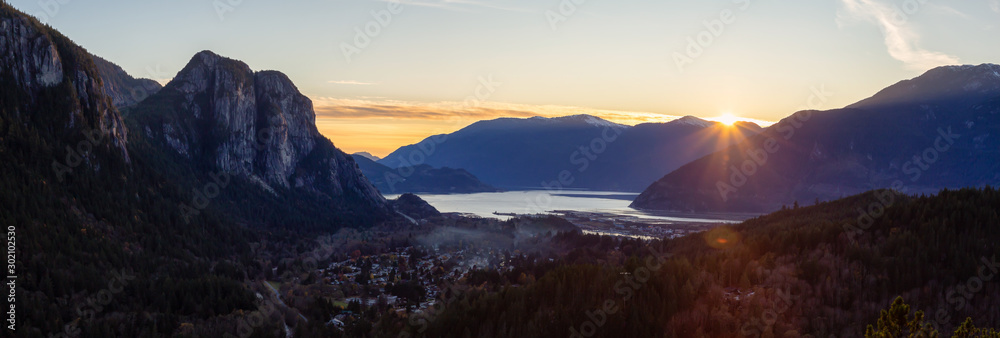 Squamish, North of Vancouver, British Columbia, Canada. Beautiful Aerial Panoramic View from the top of the Mountain of a small town surrounded by Canadian Nature during Autumn Sunset.