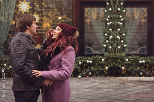 Loving couple in festive Christmas city celebrate the New Year. Romantic walk in winter. Having fun in winter christmas fair market decorations at central square city. Vacation and holiday concept
