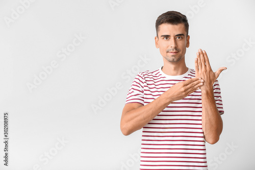 Φωτογραφία Young deaf mute man using sign language on white background