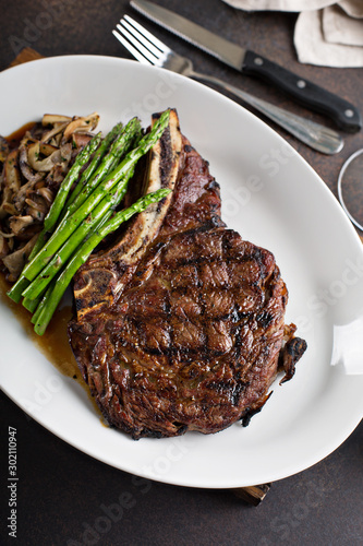 Bone-in ribeye beef steak sliced with mushrooms and asparagus photo