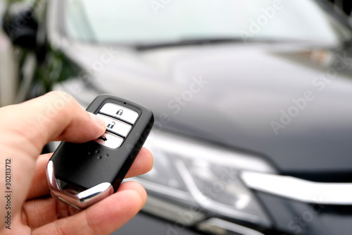 Man hand holding the car remote, he push the remote control to open the car door