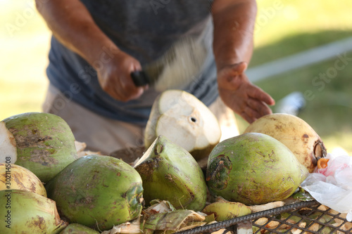 Man chopping green coconut with a machete