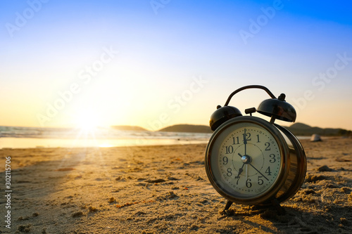 Morning of a new day, alarm clock on the beach sunlight in morning. Health and holiday concept.