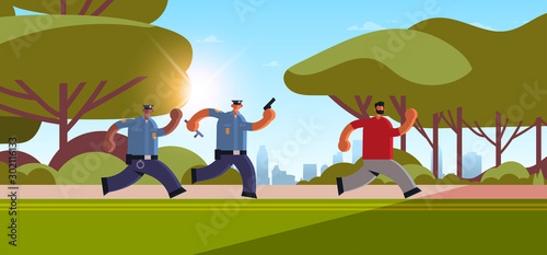 police officers with pistols pursuing burglar criminal running away from policemen in uniform security authority justice law service concept urban park cityscape background horizontal full length