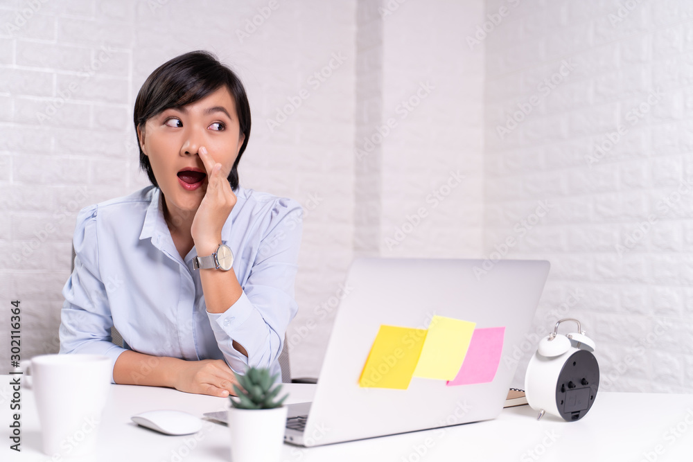 Woman sitting at home office using computer laptop and saying secret news