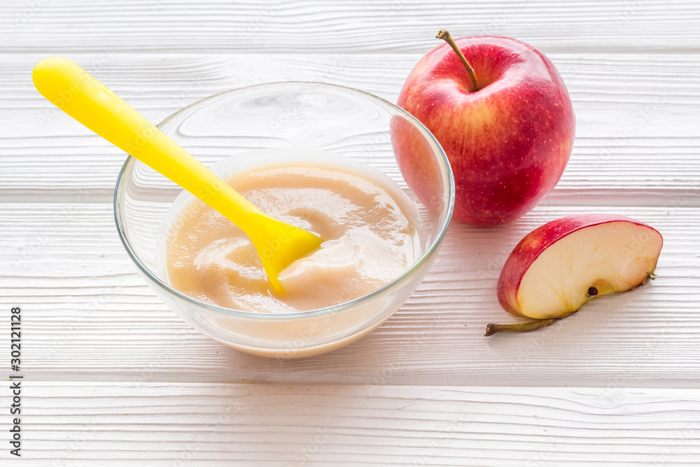 Fototapeta premium Apple puree for feed babies on white wooden background