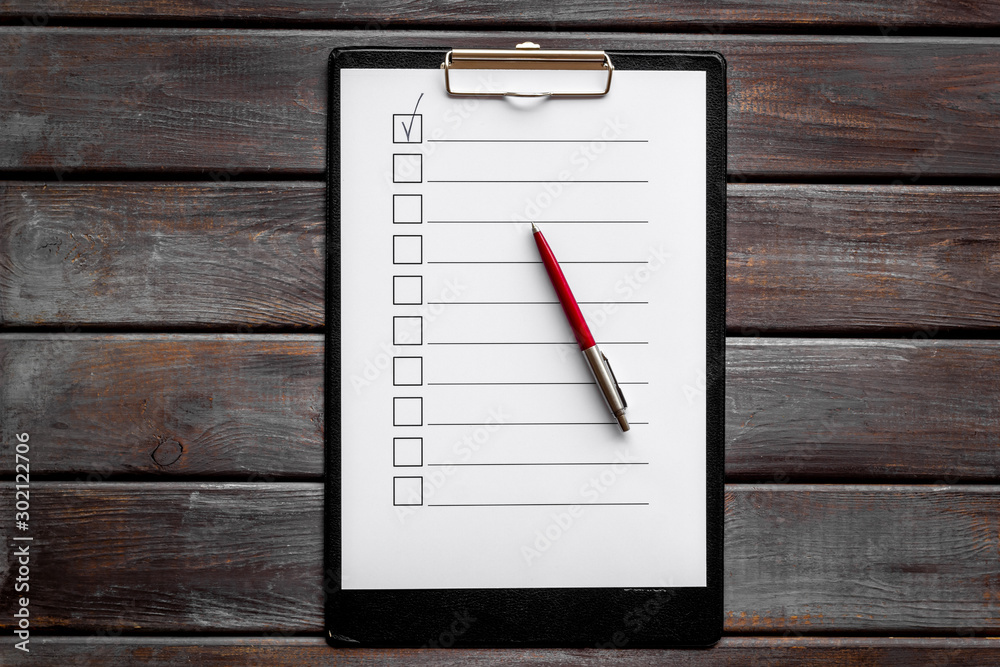 Empty check list ready to fill on dark wooden background top view Empty check list ready to fill on dark wooden background top view