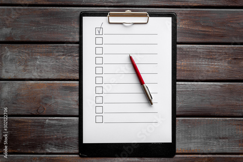 Empty check list ready to fill on dark wooden background top view photo