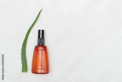 Aloe vera leaves and essential oil jar on white background.