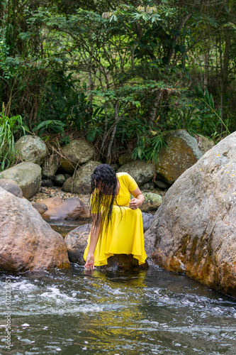 beautiful woman in yellow dress touching the river water