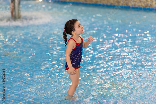 happy little girl in the pool of the water park. Child learns to swim. teaching a child to swim