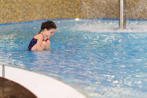 happy little girl in the pool of the water park. Child learns to swim. teaching a child to swim