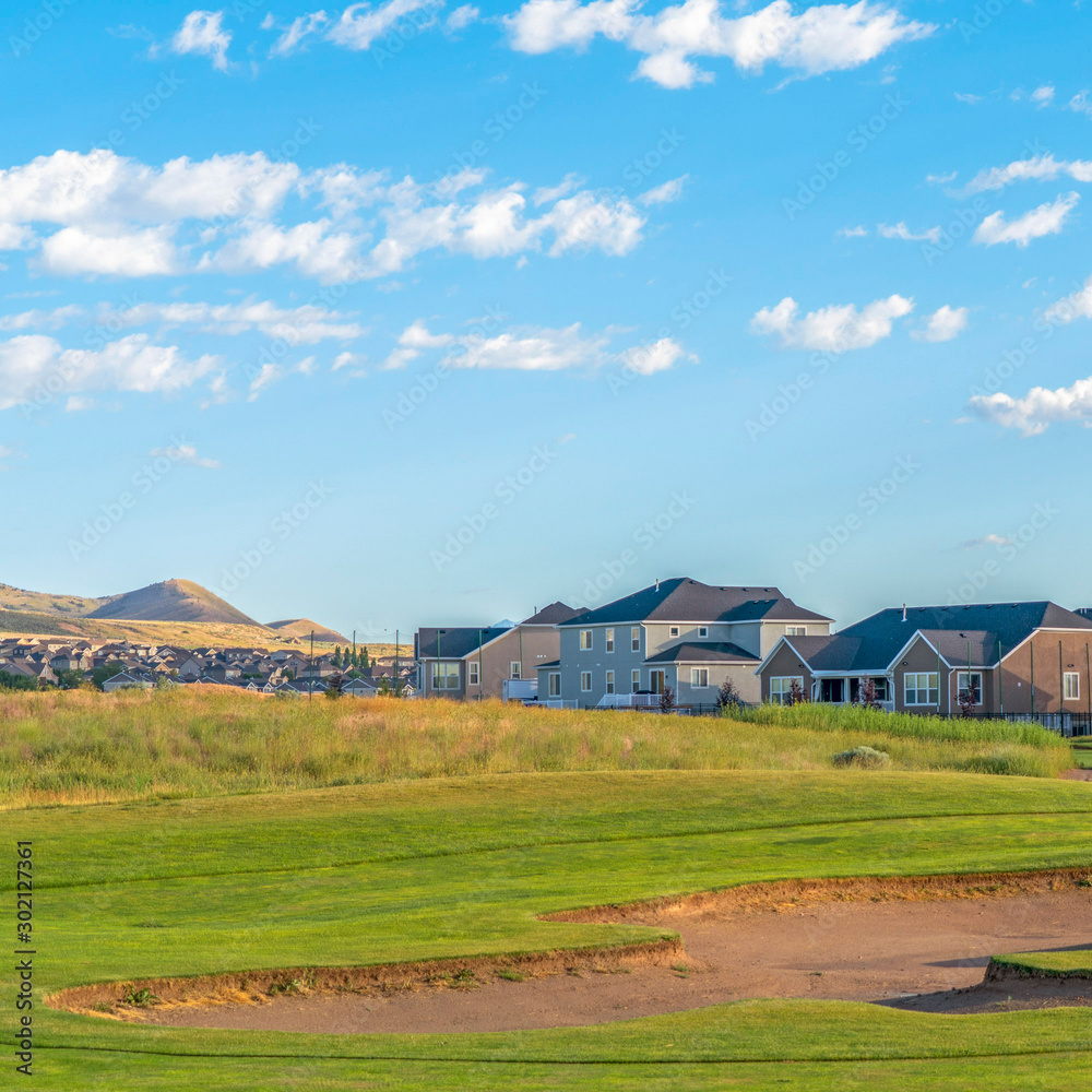 Square Golf course and houses with distant mountain and blue sky view on a sunny day