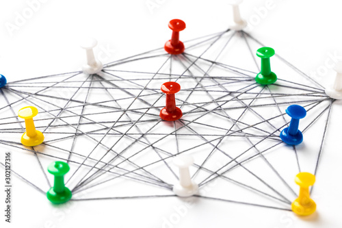 Network with colorful pins and string, linked together with string on a white background suggesting a network of connections.
