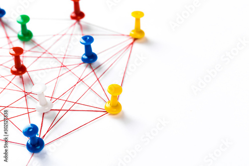 Network with colorful pins and string, linked together with string on a white background suggesting a network of connections.